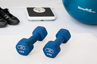 Blue 2kg dumbbells with fitness equipment on white background