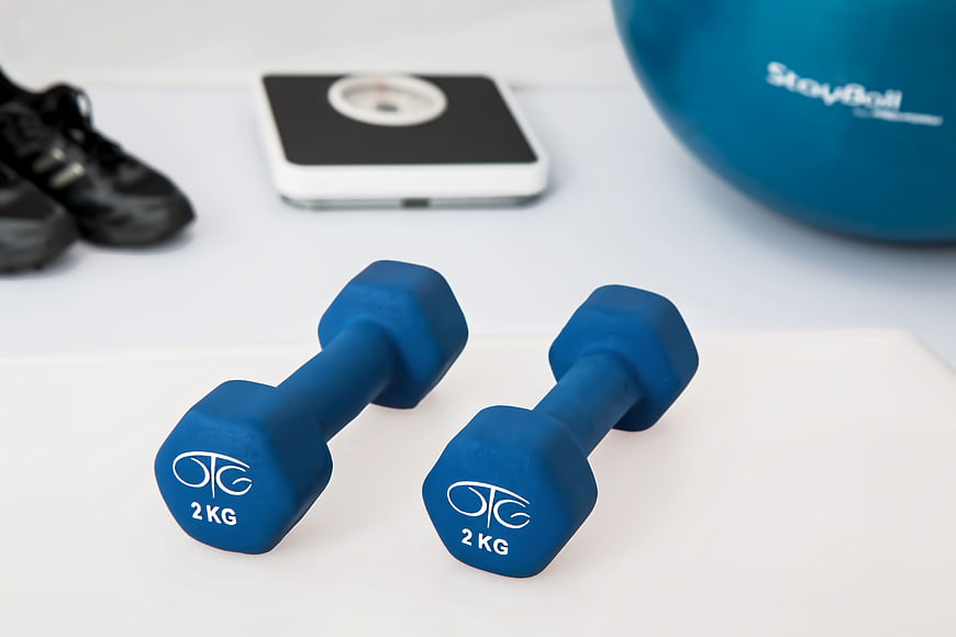 Blue 2kg dumbbells with fitness equipment on white background