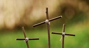 Three rustic wooden crosses tied with string on blurred green background