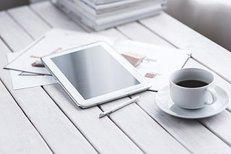 White tablet and coffee on wooden workspace