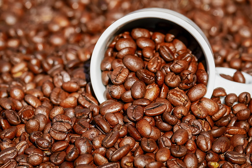 Roasted Coffee Beans Spilling from White Cup