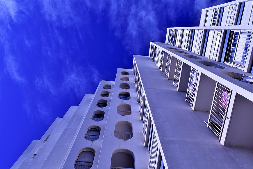 Low angle view of white Mediterranean apartment building against blue sky