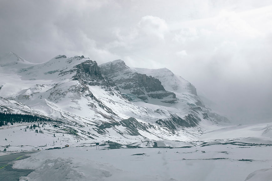 Snowy mountain landscape with clouds and winter valley