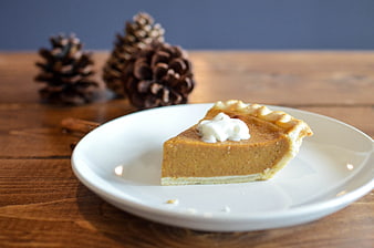 Slice of pumpkin pie with whipped cream on white plate
