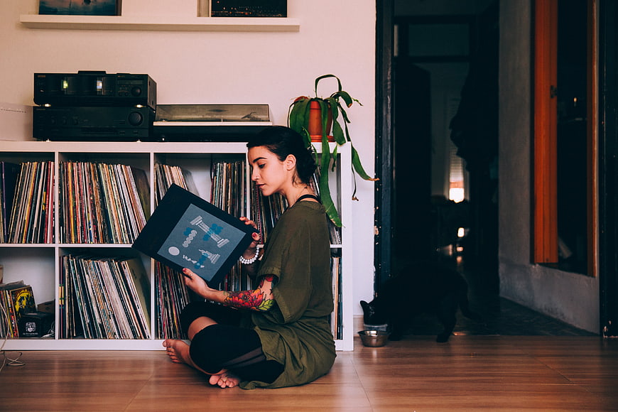 Woman with tattoos browsing vinyl records in living room