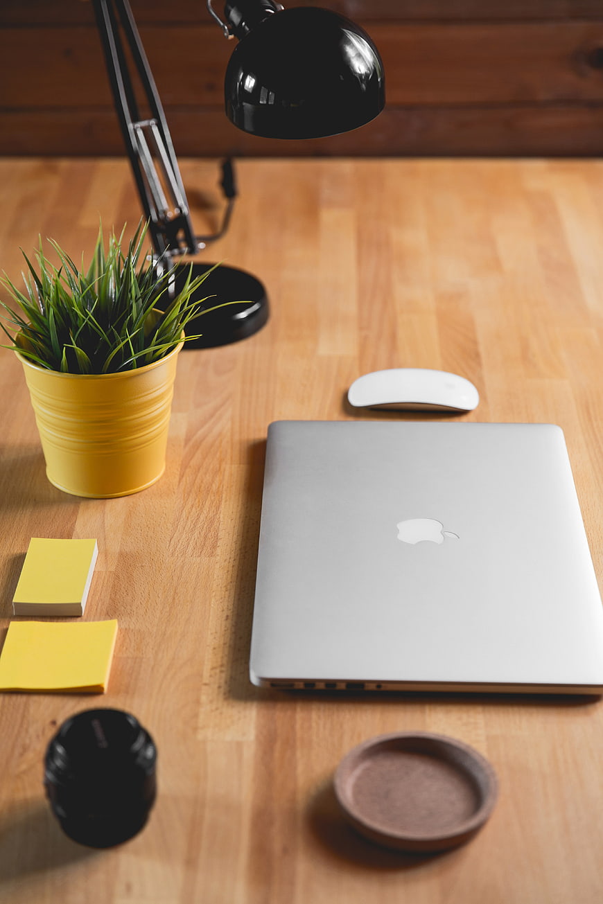 Minimalist wooden desk setup with laptop, lamp, and plant