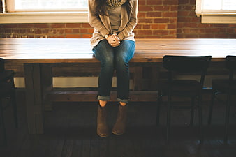 Woman sitting on wooden table in rustic loft interior