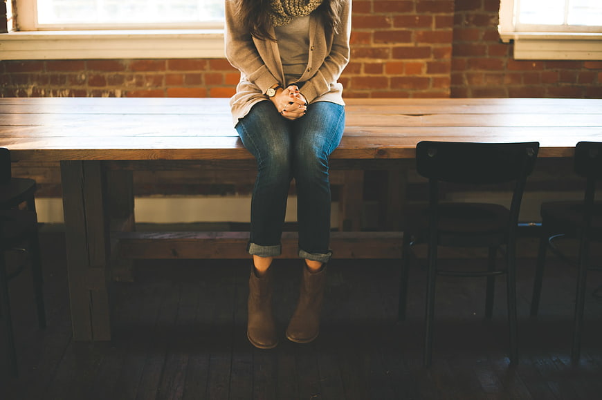 Woman sitting on wooden table in rustic loft interior