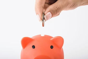 Hand Dropping Coin Into Red Piggy Bank On White Background