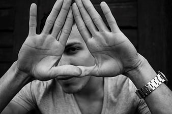 Black and white portrait of man framing face with hands