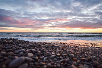 Low angle sunset seascape with pebbles and waves