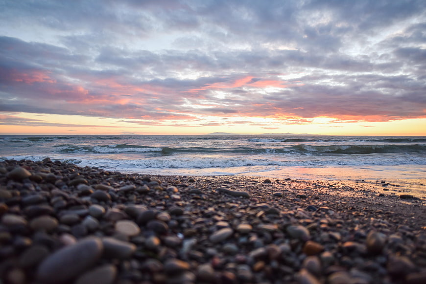 Low angle sunset seascape with pebbles and waves