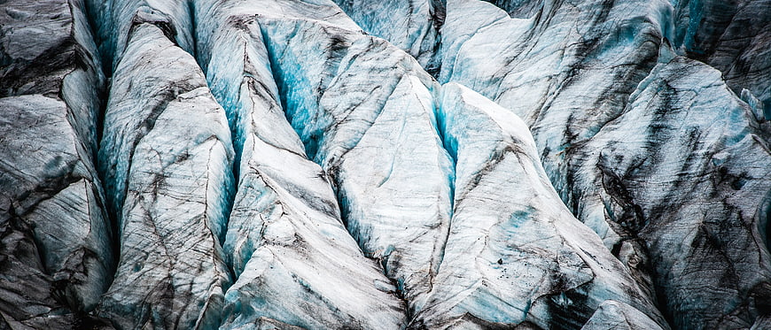Close-up of textured glacier ice with deep blue crevasses