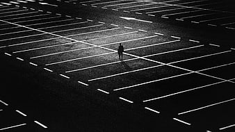High angle view of lone man walking in empty parking lot at night
