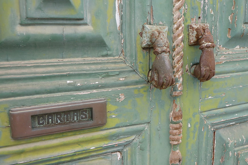 Vintage Green Wooden Door with Peeling Paint and Hand Knocker
