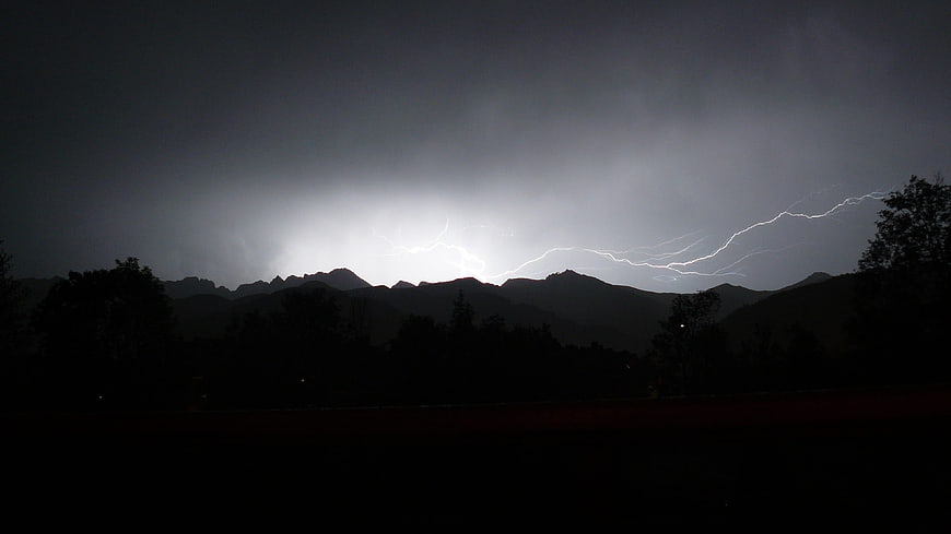Dramatic lightning bolt striking over dark mountain silhouette