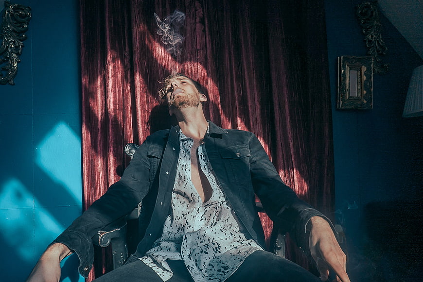 Man Smoking Cigarette in Dramatic Blue and Red Lighting
