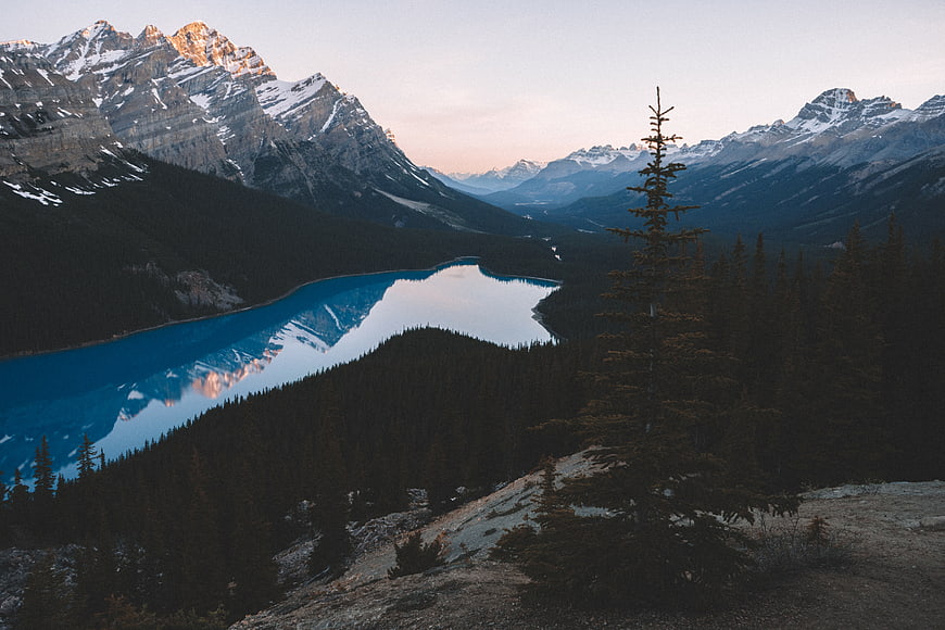 Serene turquoise mountain lake reflecting snow-capped peaks at sunrise
