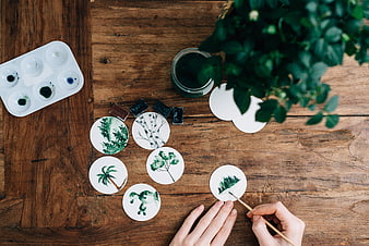Top view of hands painting nature scenes on round paper