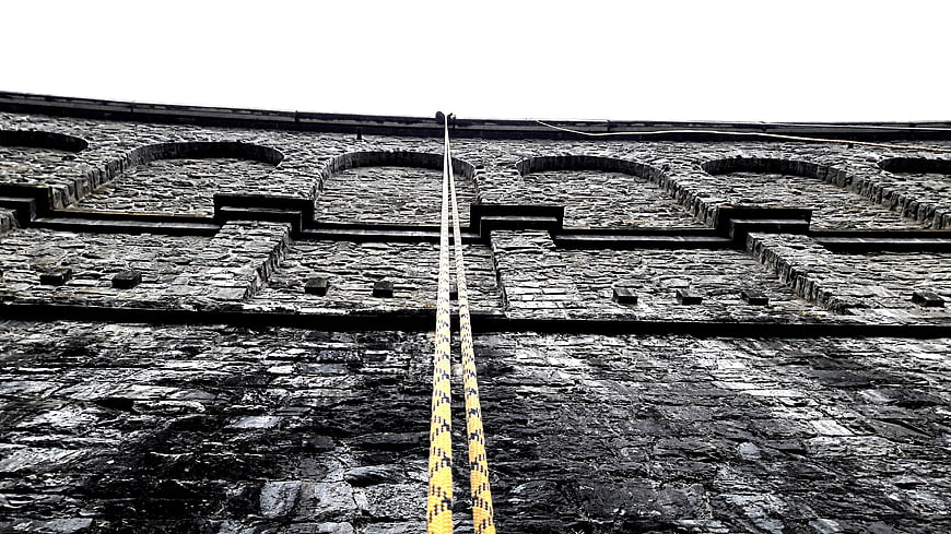 Yellow Ropes on Textured Stone Dam Wall