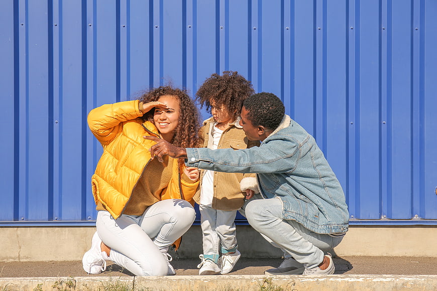 Happy African American Family Playing Outdoors Against Blue Wall