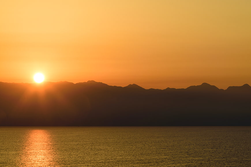 Golden Sunset Over Mountain Silhouette and Calm Water