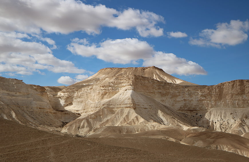 White chalky desert mountains under blue sky with clouds