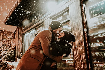 Romantic couple hugging in snow outside flower shop