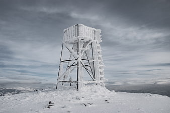 Ice-covered metal tower on snowy mountain peak