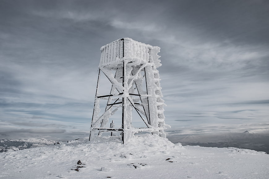 Ice-covered metal tower on snowy mountain peak
