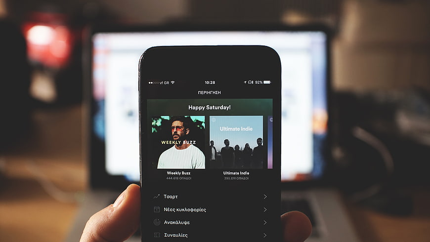 Hand holding smartphone with music app interface