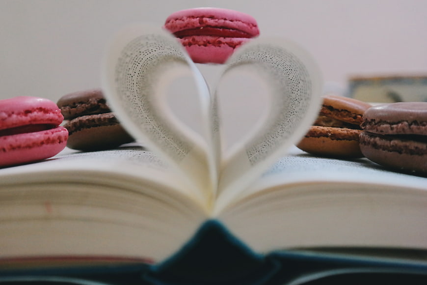 Open book with heart-shaped pages and colorful macarons
