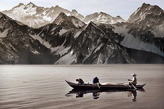 Men rowing boat on lake with snowy mountains