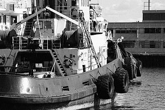 Black and white photo of a tugboat docked at a harbor