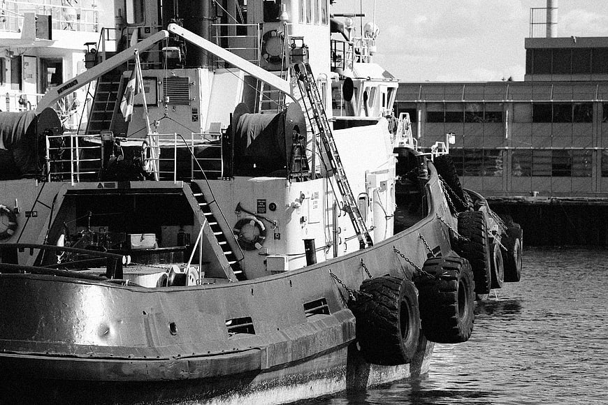 Black and white photo of a tugboat docked at a harbor