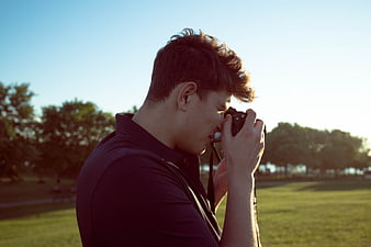 Young Man Taking Photo with Camera in Park
