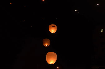 Three glowing sky lanterns floating in the night sky