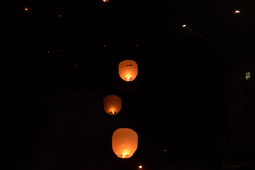 Three glowing sky lanterns floating in the night sky