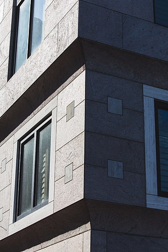 Modern building corner with stone facade and windows