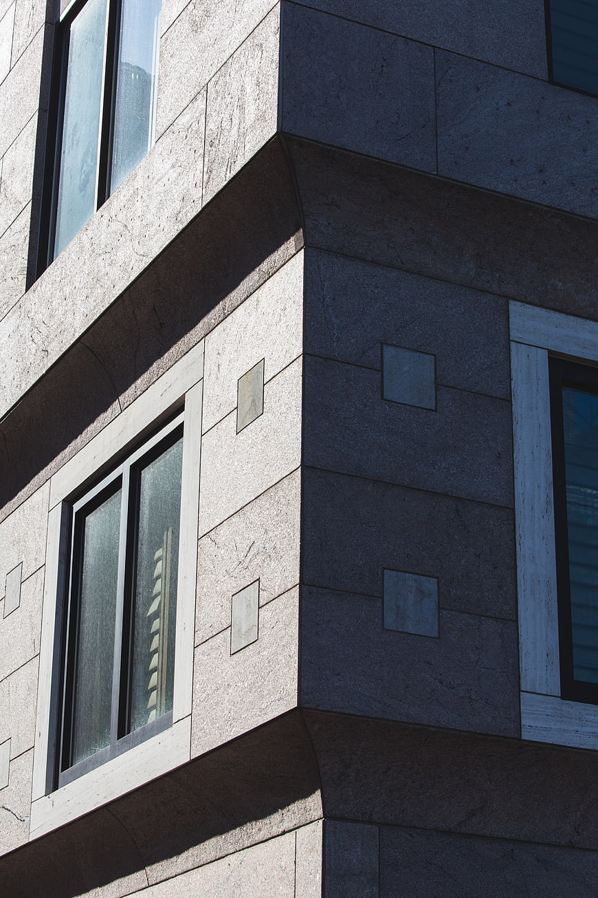 Modern building corner with stone facade and windows