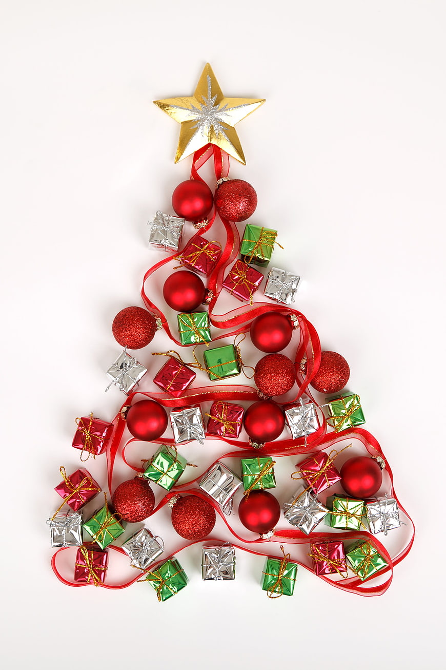 Flat lay Christmas tree made of red baubles, gifts, and gold star