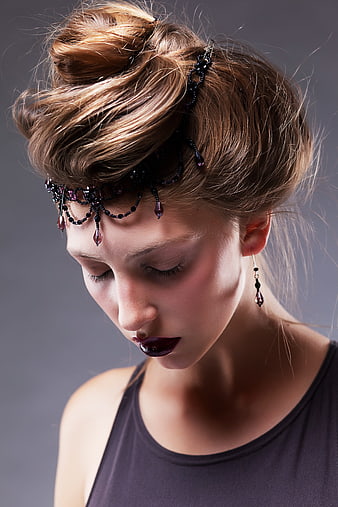Woman with ornate beaded headpiece and dark lipstick