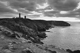 Dramatic Black and White Lighthouse on Rocky Coastal Cliffs