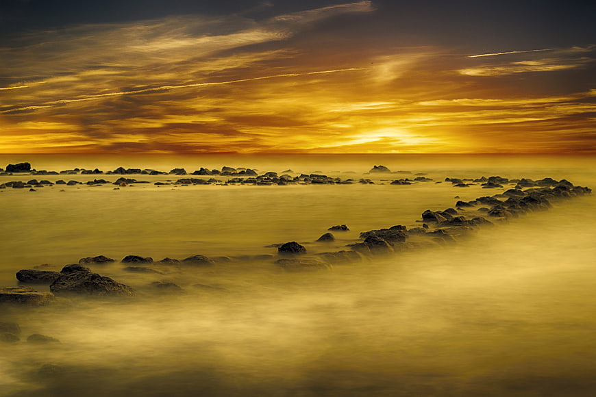 Golden Sunset Over Misty Rocky Coastline