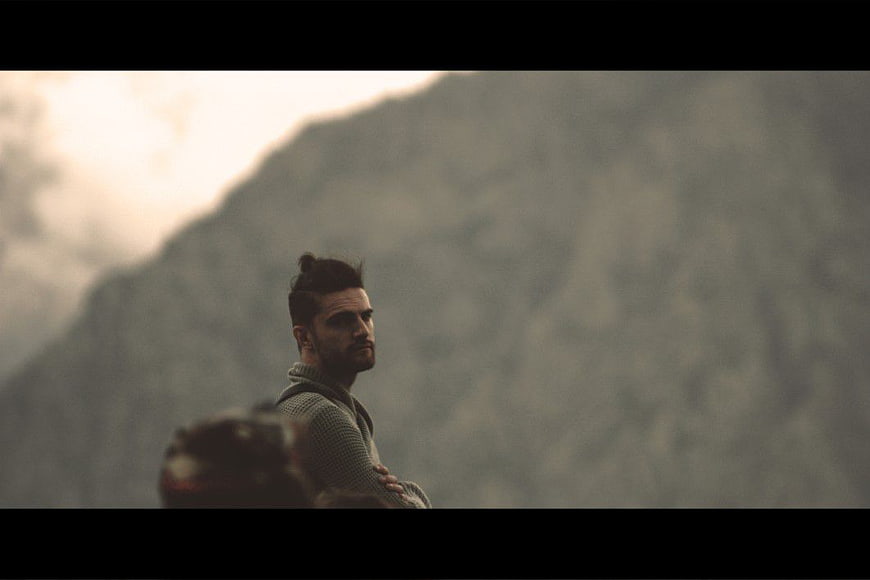 Man with Top Knot Looking at Mountain Landscape