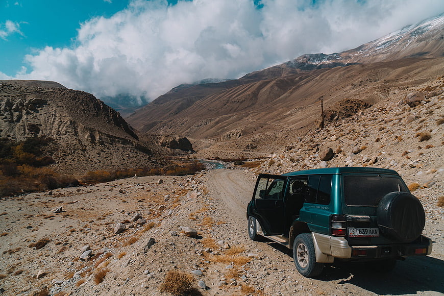 Green SUV parked on mountain road with open door