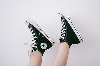 Green Converse High Tops on Legs Against White Background