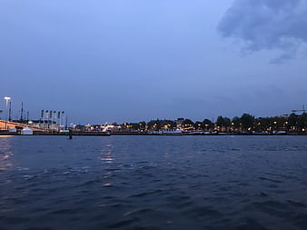 Amsterdam harbor at dusk with boats and city lights