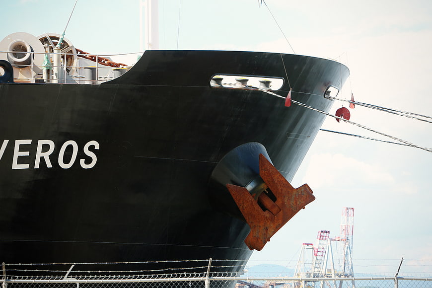 Close-up of black cargo ship bow with rusty anchor