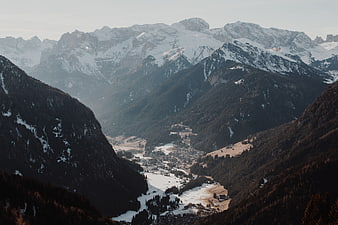 Snowy Alpine Valley with Mountain Village and Forested Slopes